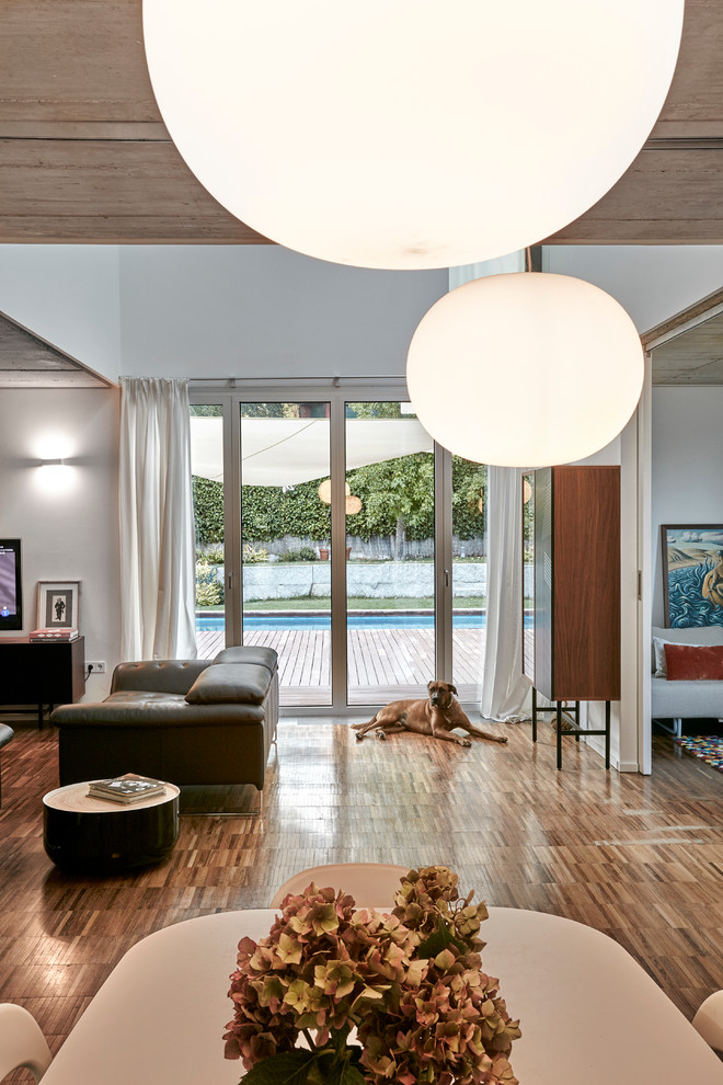Идея дизайна: большая гостиная-столовая в стиле модернизм с белыми стенами, паркетным полом среднего тона и коричневым полом