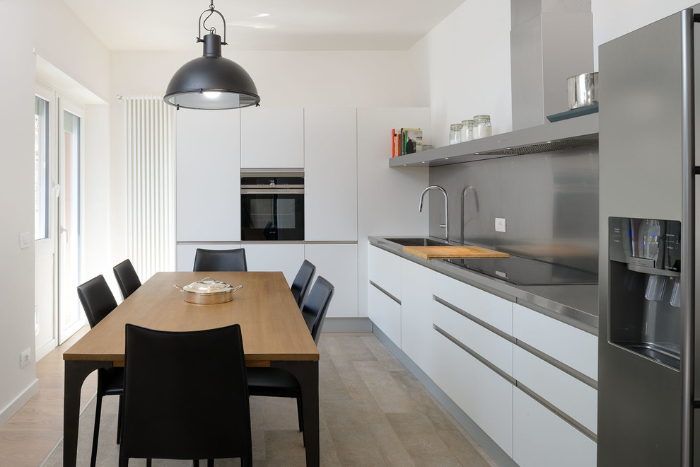 Immagine di una sala da pranzo aperta verso la cucina minimalista di medie dimensioni con pareti bianche e parquet chiaro