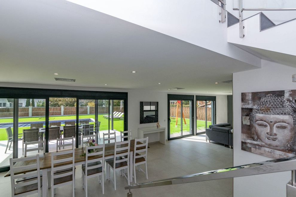Immagine di una sala da pranzo aperta verso il soggiorno contemporanea di medie dimensioni con pareti bianche, pavimento in gres porcellanato e pavimento grigio