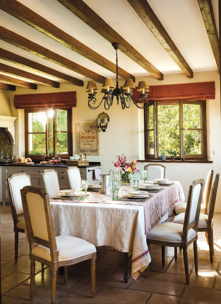 Foto di una sala da pranzo aperta verso la cucina country con pareti beige, pavimento marrone e pavimento in pietra calcarea
