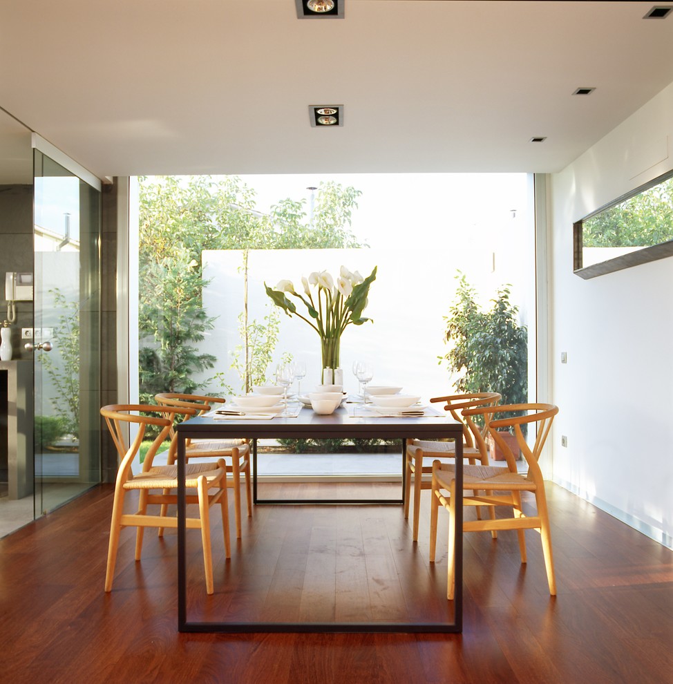 Immagine di una sala da pranzo minimalista chiusa con pareti bianche e pavimento in legno massello medio