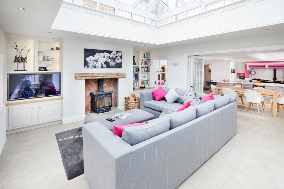 This is an example of a traditional conservatory in London with a wood burning stove, a brick fireplace surround, a glass ceiling and grey floors.