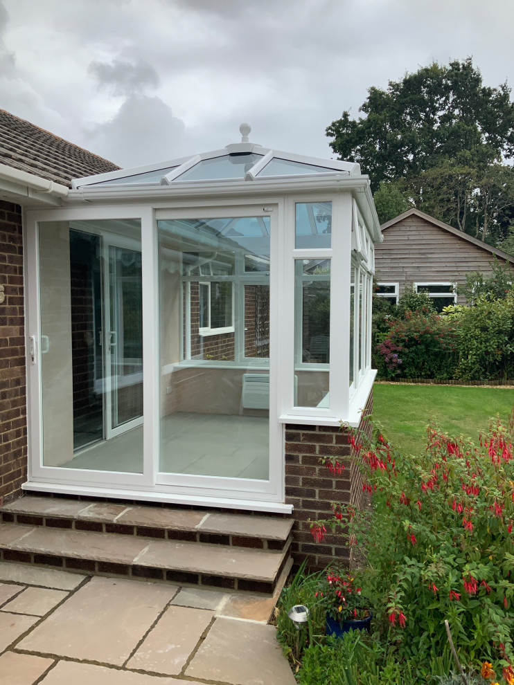This is an example of a small classic conservatory in Dorset with ceramic flooring, no fireplace, a glass ceiling and grey floors.