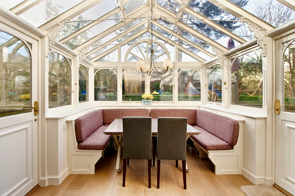 This is an example of a small traditional conservatory in London with light hardwood flooring, no fireplace and a glass ceiling.