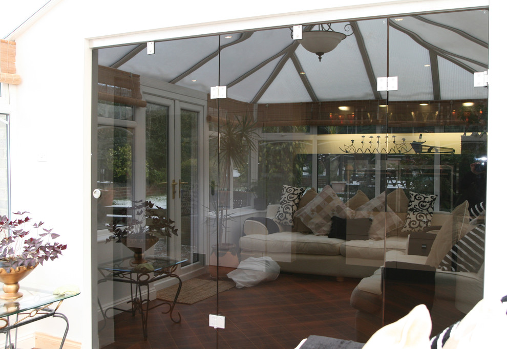 This is an example of a contemporary conservatory in Other with medium hardwood flooring and a glass ceiling.
