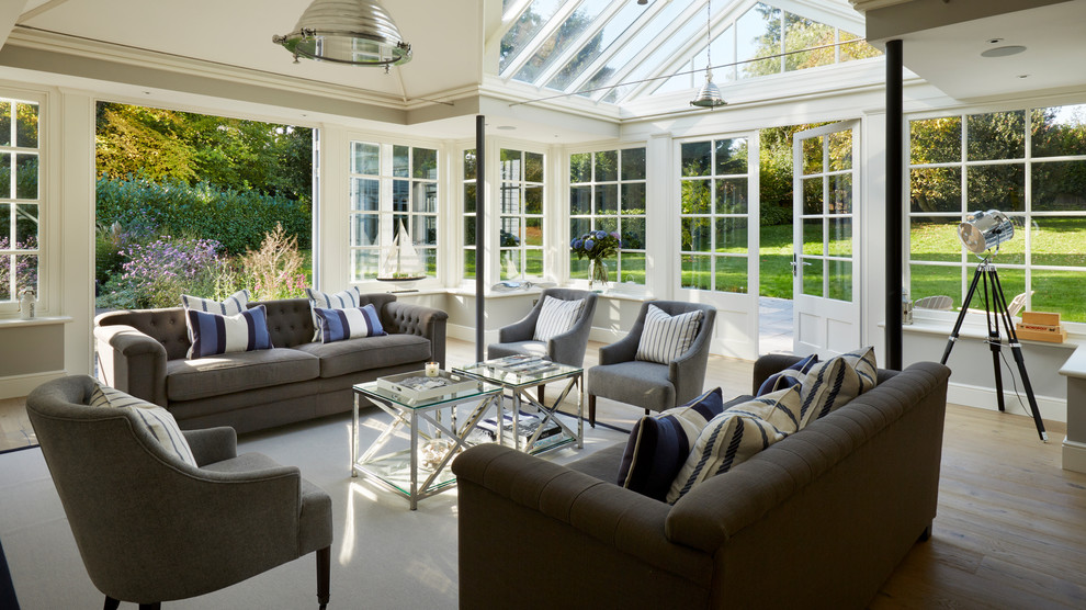 This is an example of a classic conservatory in Essex with light hardwood flooring, a glass ceiling and beige floors.
