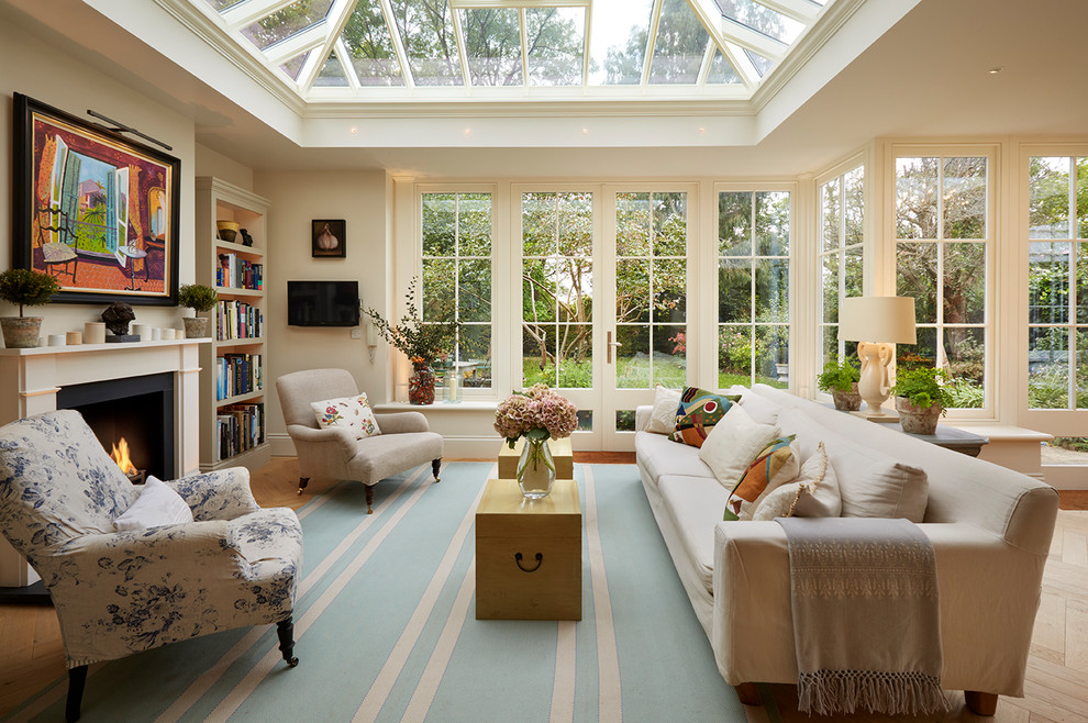 Idee per una veranda tradizionale con parquet chiaro, camino classico e soffitto in vetro