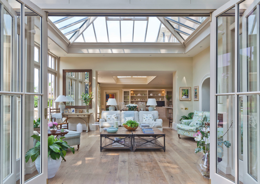 This is an example of a large traditional conservatory in Other with light hardwood flooring, no fireplace, a glass ceiling and beige floors.