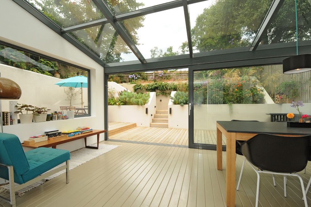 Mid-century modern painted wood floor and beige floor sunroom photo in London with a glass ceiling