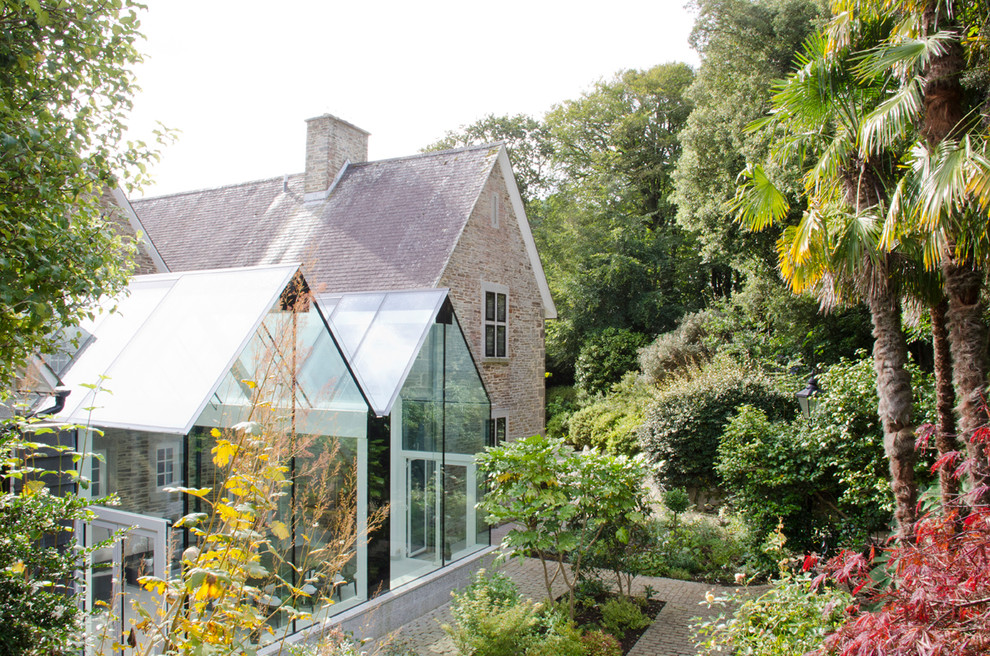 Immagine di una grande veranda design con pavimento in pietra calcarea, soffitto in vetro e pavimento beige