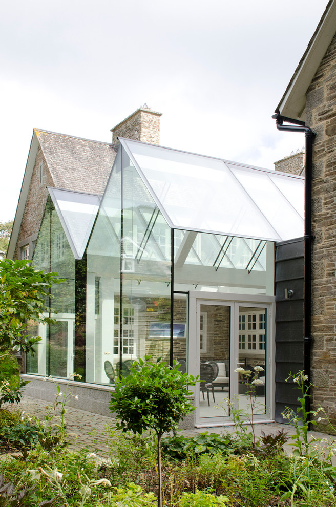 This is an example of a large contemporary conservatory in Cornwall with limestone flooring, a glass ceiling and beige floors.