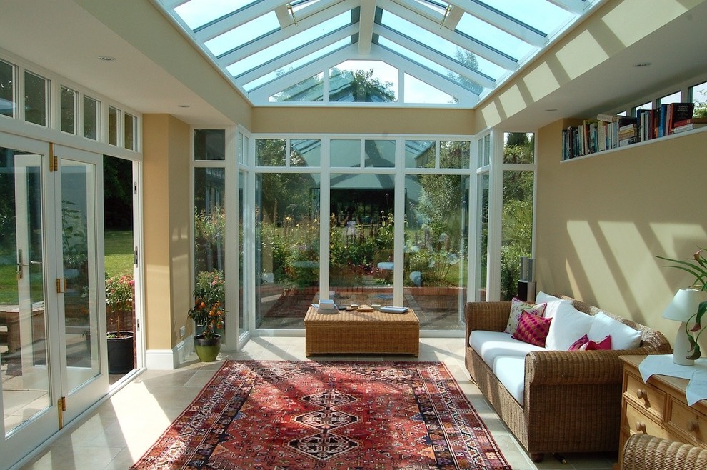 Exemple d'une grande véranda tendance avec un sol en travertin, un plafond en verre et un sol beige.