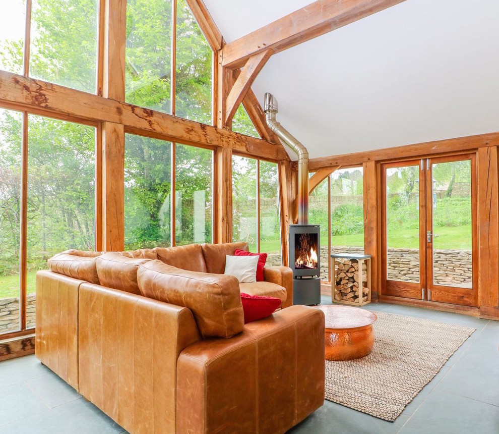 Foto di una grande veranda country con pavimento in ardesia, stufa a legna, soffitto in vetro e pavimento grigio