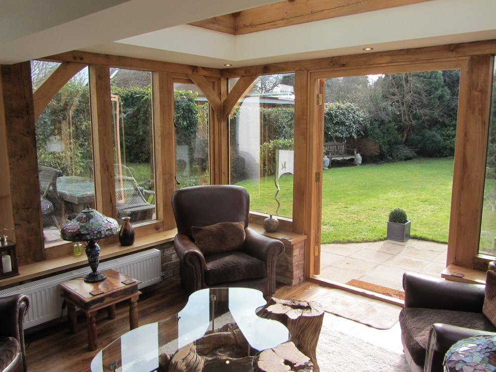 Example of a cottage medium tone wood floor and orange floor sunroom design in West Midlands with a skylight