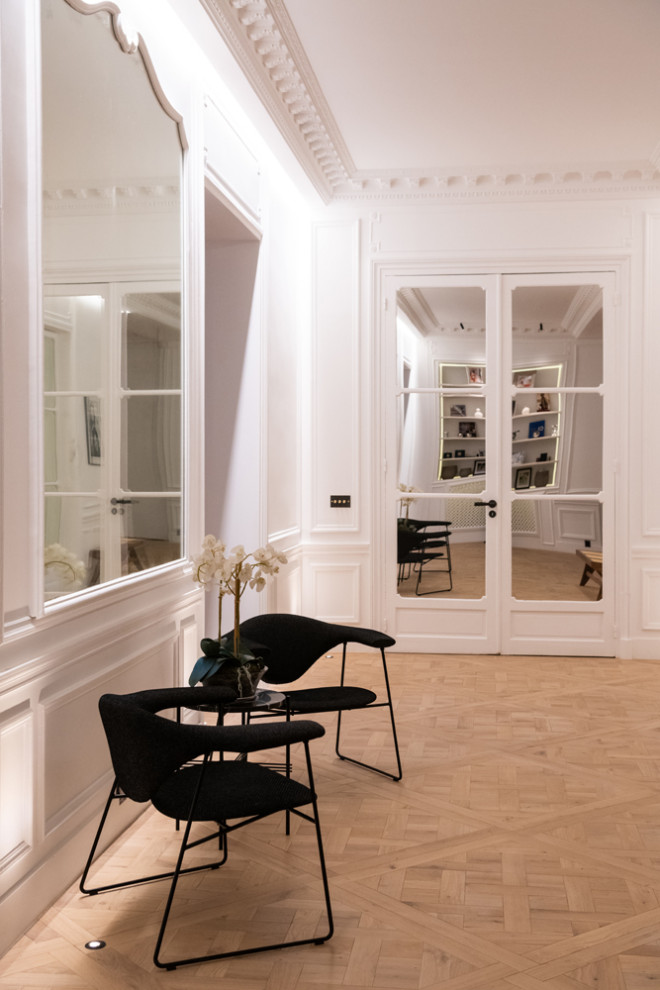 Inspiration pour un grand couloir design avec un mur blanc, parquet clair et un sol beige.