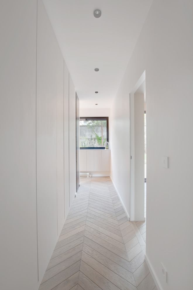 Idee per un grande ingresso o corridoio minimal con pareti beige e pavimento in legno massello medio