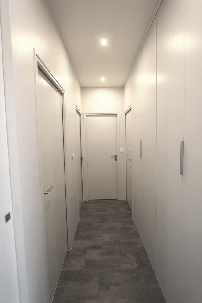 Réalisation d'un couloir design de taille moyenne avec un mur blanc, sol en stratifié et un sol gris.