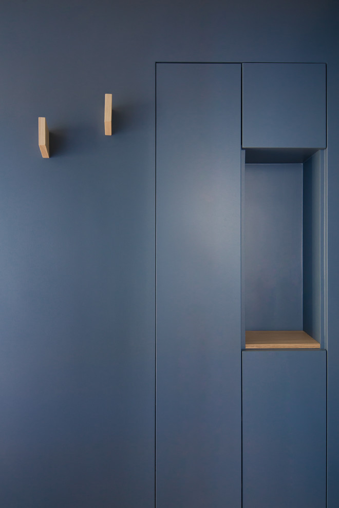 Inspiration för en liten minimalistisk hall, med blå väggar och brunt golv