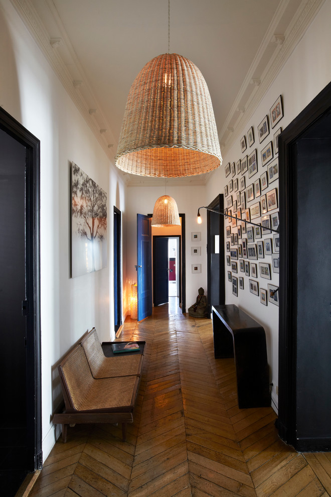 Idée de décoration pour un grand couloir design avec un mur blanc et un sol en bois brun.