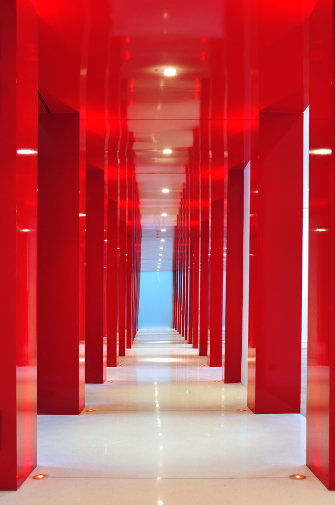 Idée de décoration pour un grand couloir design avec un mur rouge et un sol en travertin.