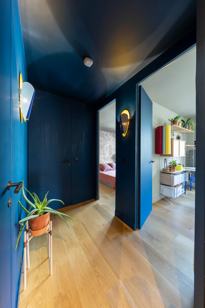 Kleiner Moderner Flur mit blauer Wandfarbe, hellem Holzboden und braunem Boden in Paris