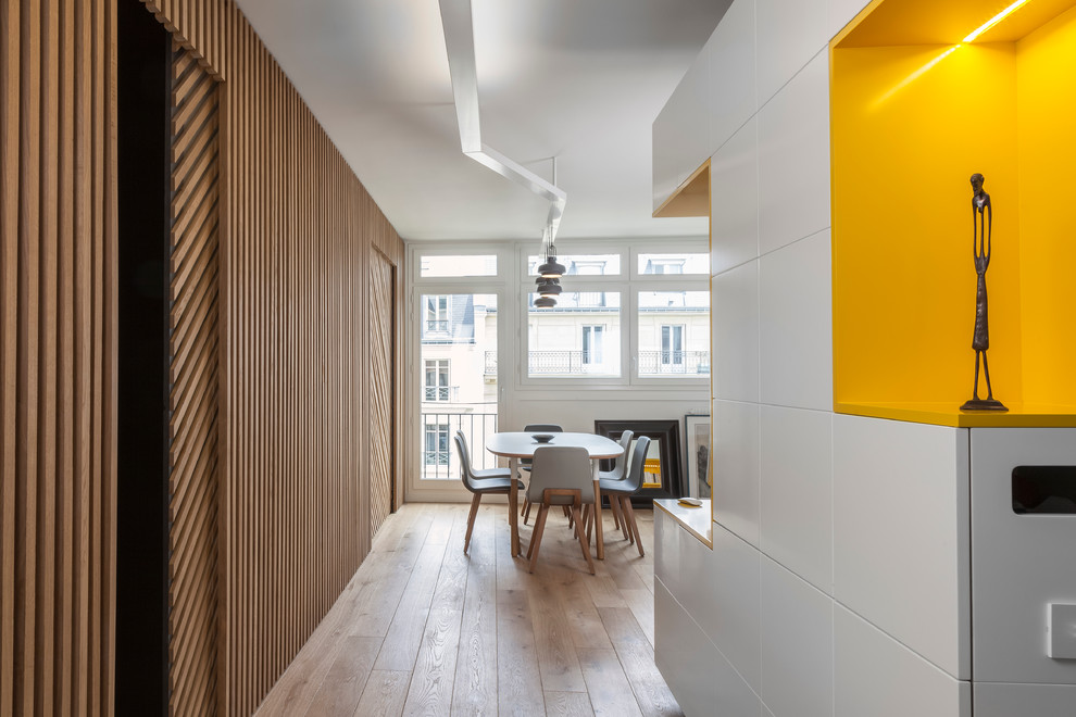 Idée de décoration pour un couloir design avec un mur jaune et parquet clair.