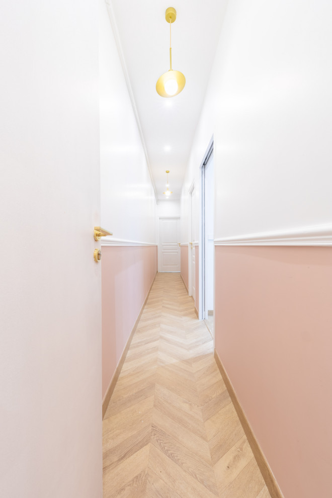 Cette photo montre un couloir tendance de taille moyenne avec un mur rose, parquet clair et un sol beige.