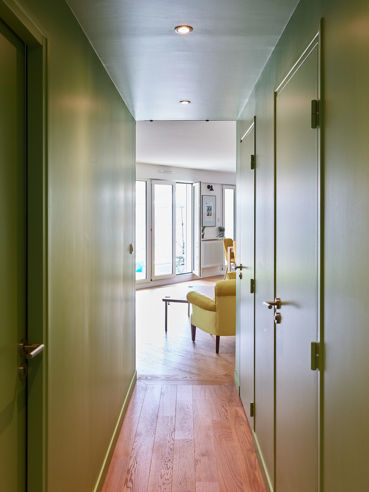 Diseño de recibidores y pasillos actuales de tamaño medio con paredes verdes, suelo de madera clara y suelo marrón