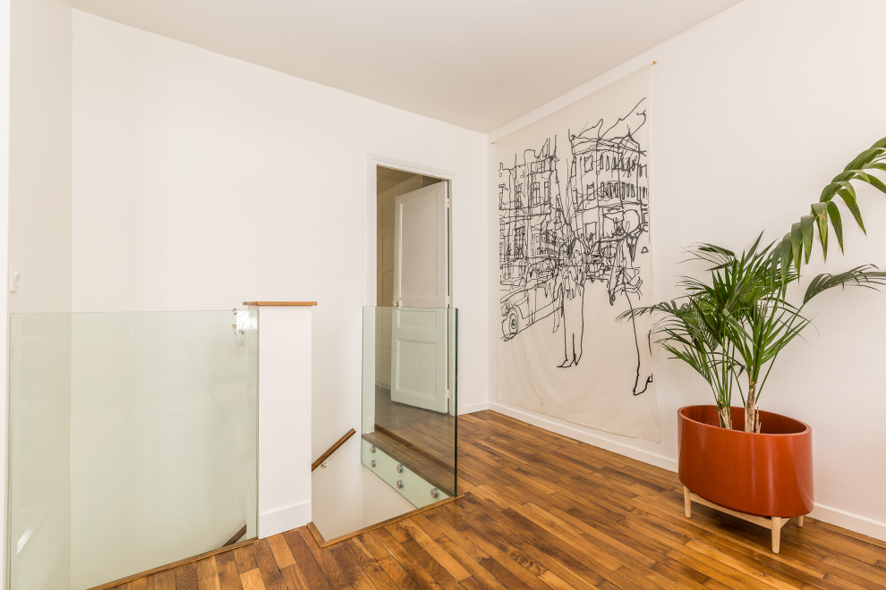 Cette image montre un couloir design de taille moyenne avec un mur blanc, un sol en bois brun et un sol marron.