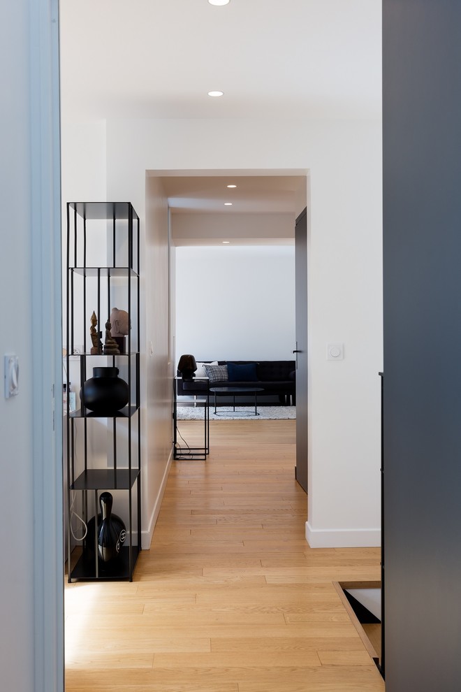 Example of a trendy light wood floor hallway design in Paris with white walls