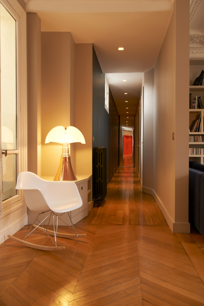 Exemple d'un grand couloir tendance avec un mur beige, parquet clair et un sol marron.