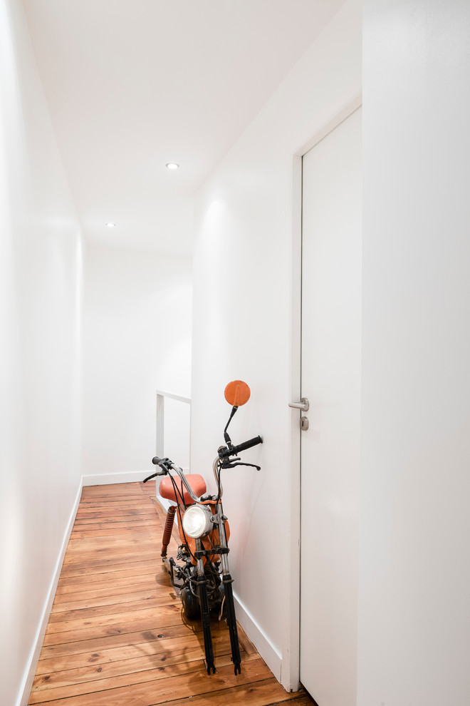 Cette image montre un petit couloir minimaliste avec un mur blanc et parquet clair.