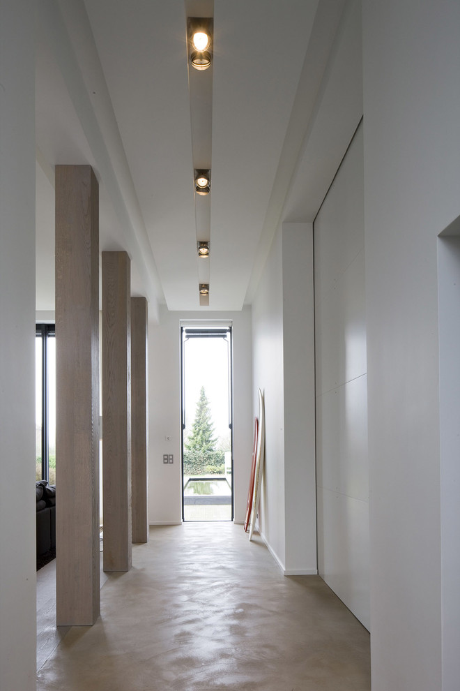 Diseño de recibidores y pasillos contemporáneos grandes con paredes blancas y suelo de cemento