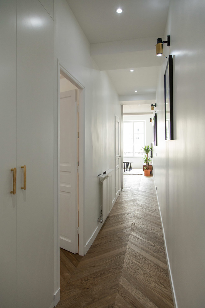Esempio di un piccolo ingresso o corridoio minimalista con pareti bianche, pavimento in legno massello medio e pavimento marrone
