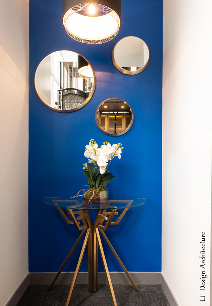 パリにあるお手頃価格の小さなトランジショナルスタイルのおしゃれな廊下 (青い壁、カーペット敷き、グレーの床) の写真
