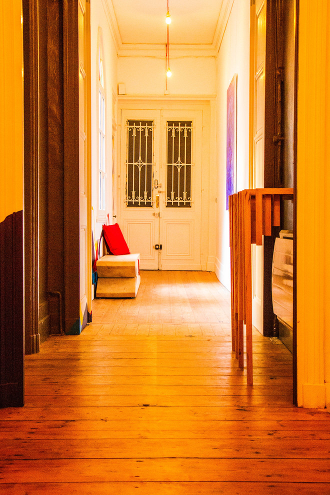 Cette photo montre un petit couloir tendance avec un mur blanc, un sol en bois brun et un sol beige.