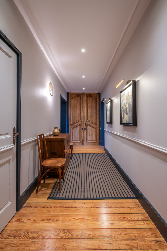 Inspiration for a large transitional light wood floor and brown floor hallway remodel in Other with gray walls