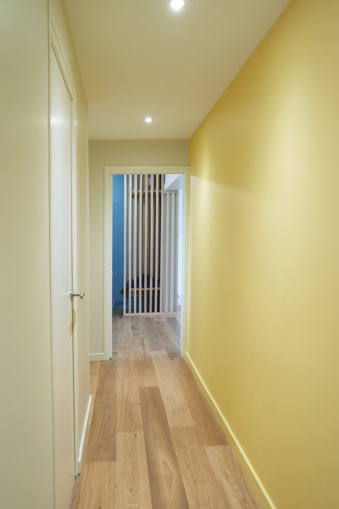 Стильный дизайн: коридор в скандинавском стиле с желтыми стенами и паркетным полом среднего тона - последний тренд