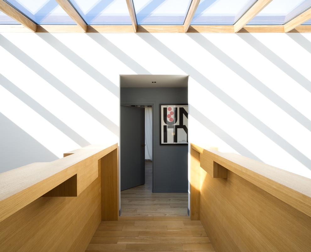 Inspiration pour un couloir design de taille moyenne avec un mur blanc et parquet clair.