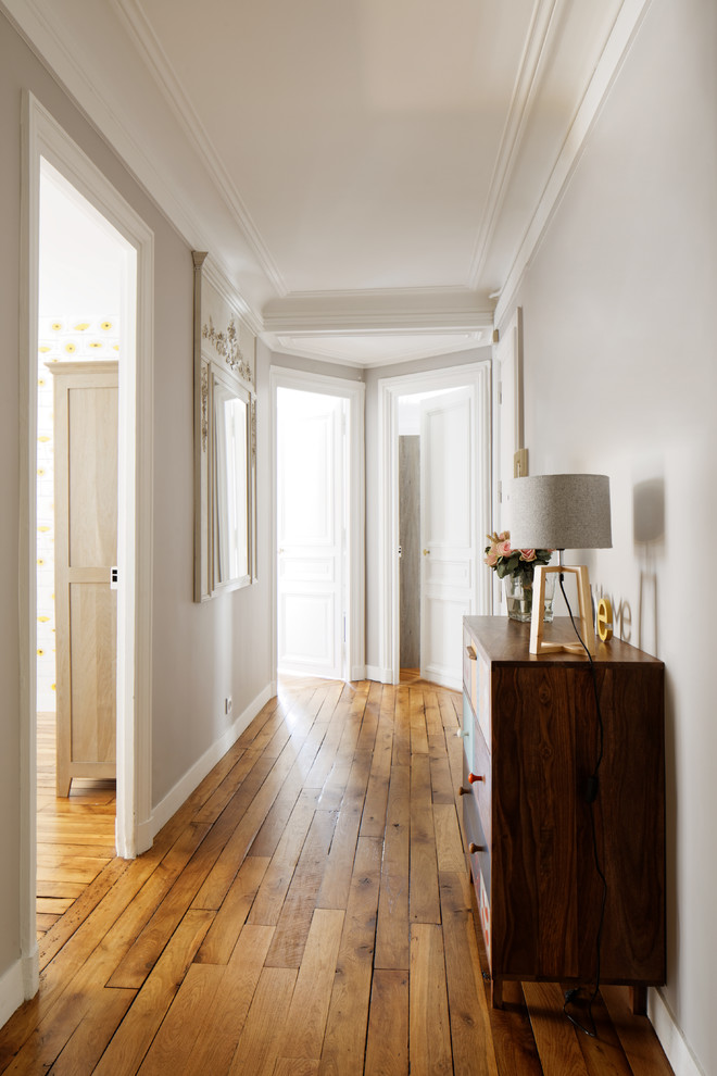 Réalisation d'un grand couloir tradition avec un mur gris et parquet clair.