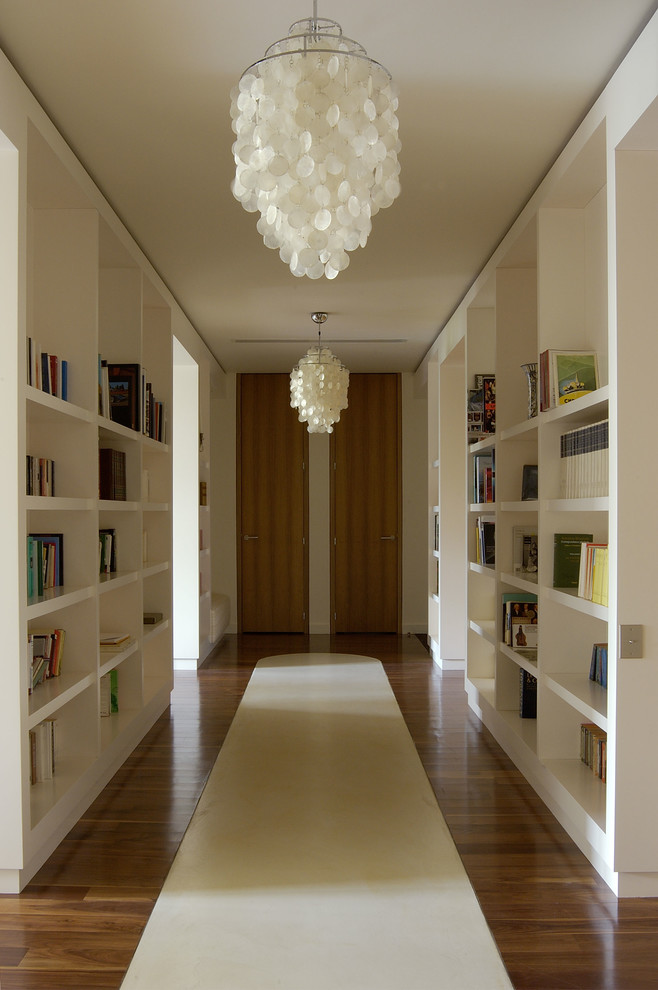 Idée de décoration pour un couloir minimaliste de taille moyenne avec un mur blanc, un sol en bois brun et un sol marron.