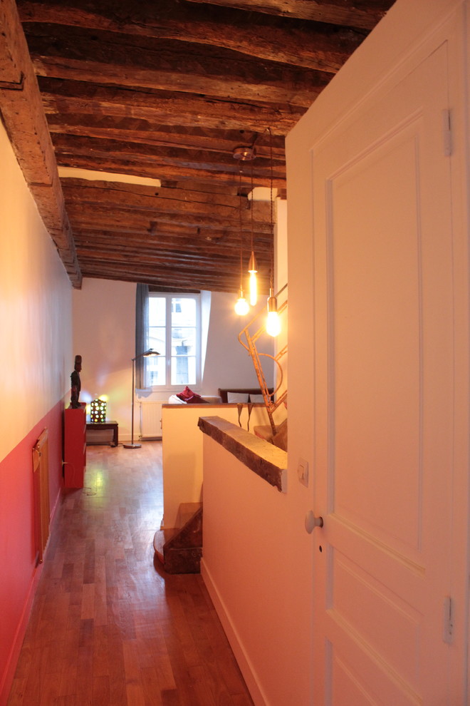 Ispirazione per un ingresso o corridoio tropicale di medie dimensioni con pareti arancioni e pavimento in legno massello medio