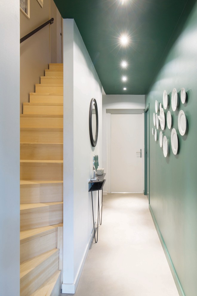 Idée de décoration pour un grand couloir design avec un mur vert, sol en béton ciré et un sol gris.