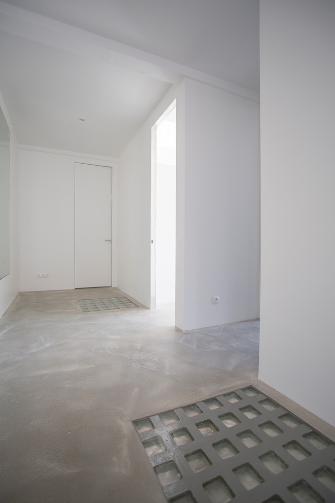 Modern inredning av en stor hall, med vita väggar, betonggolv och grått golv