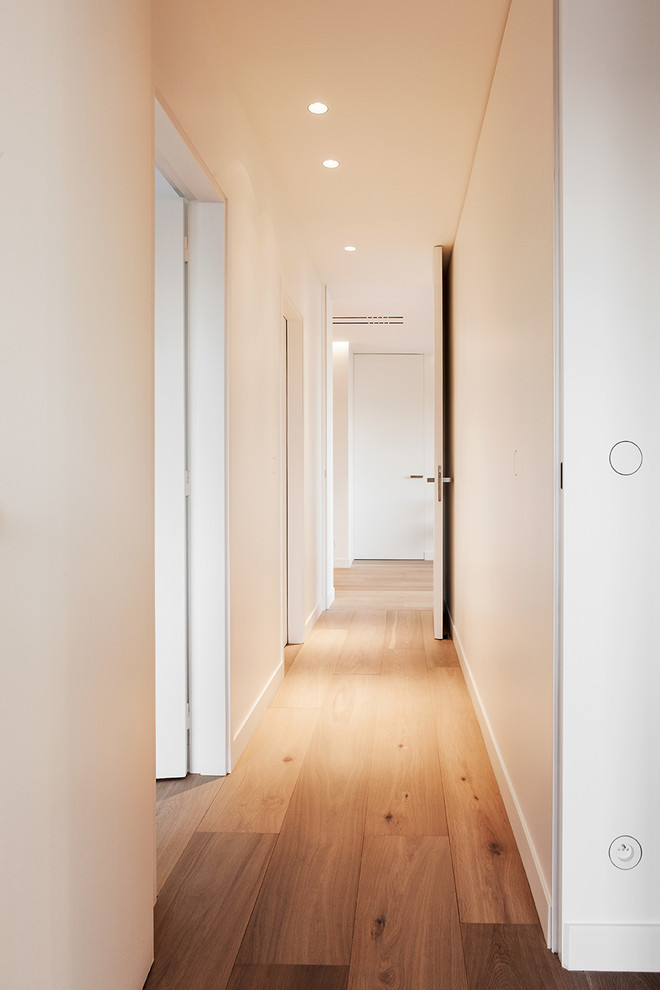 Ispirazione per un ingresso o corridoio minimal di medie dimensioni con pareti bianche, parquet chiaro e pavimento marrone