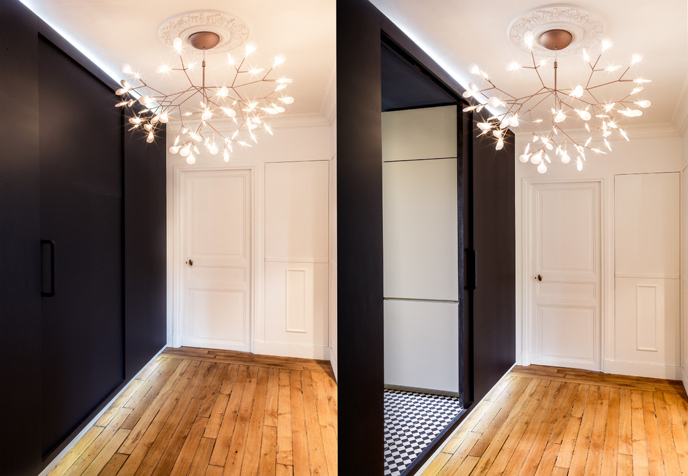 Immagine di un ingresso o corridoio minimalista di medie dimensioni con pareti nere e parquet chiaro