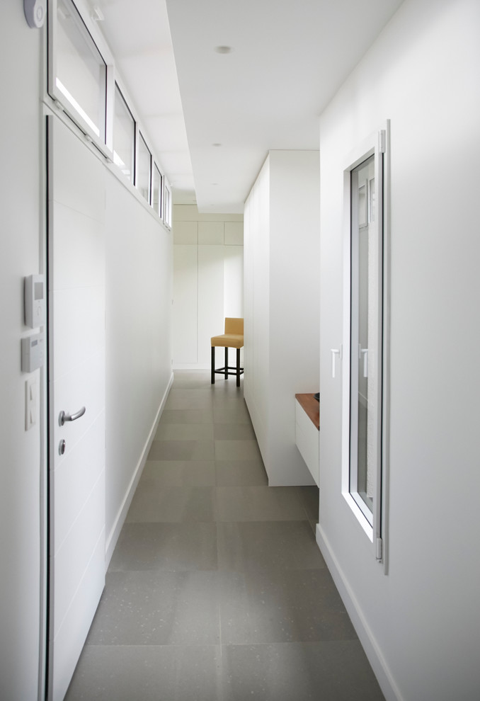 Idée de décoration pour un couloir design de taille moyenne avec un mur blanc, un sol en carrelage de céramique et un sol gris.