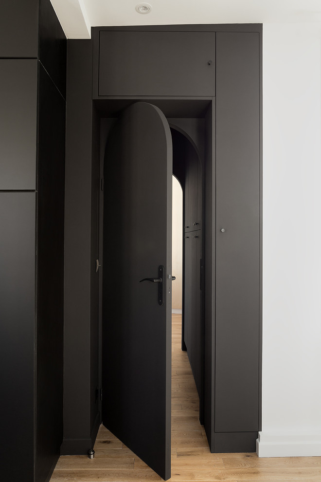 Immagine di un ingresso o corridoio tropicale di medie dimensioni con pareti nere e parquet chiaro