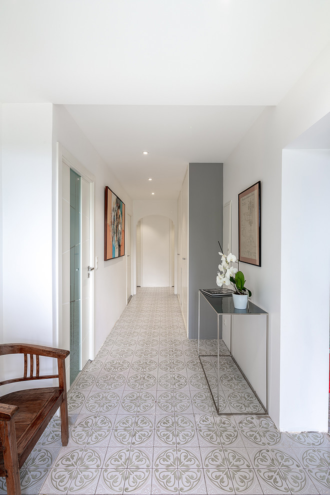 Cette image montre un couloir design avec un mur blanc et un sol gris.
