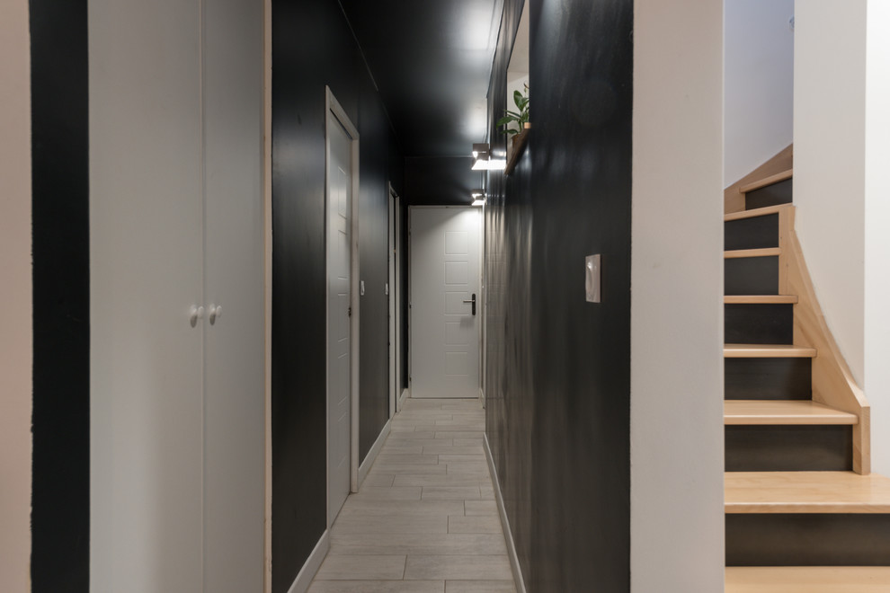 Idée de décoration pour un couloir design de taille moyenne avec un mur noir, un sol en carrelage de céramique et un sol gris.